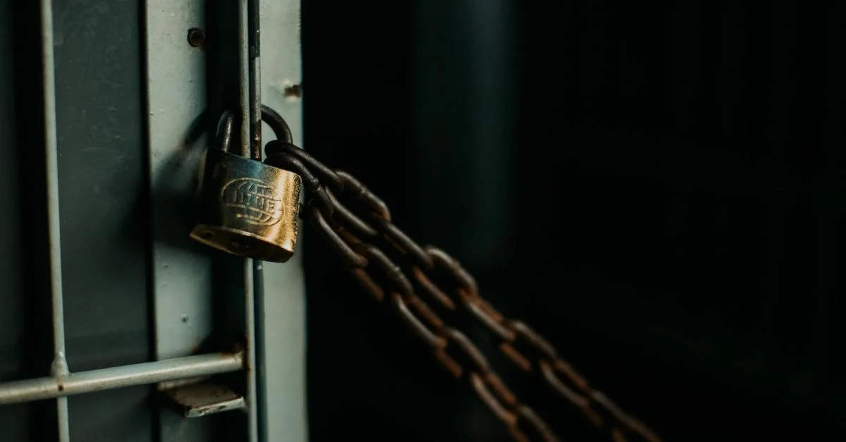 Une photo artistique en gros plan d'un cadenas usé sécurisant une chaîne sur une porte en métal, symbolisant la sécurité.